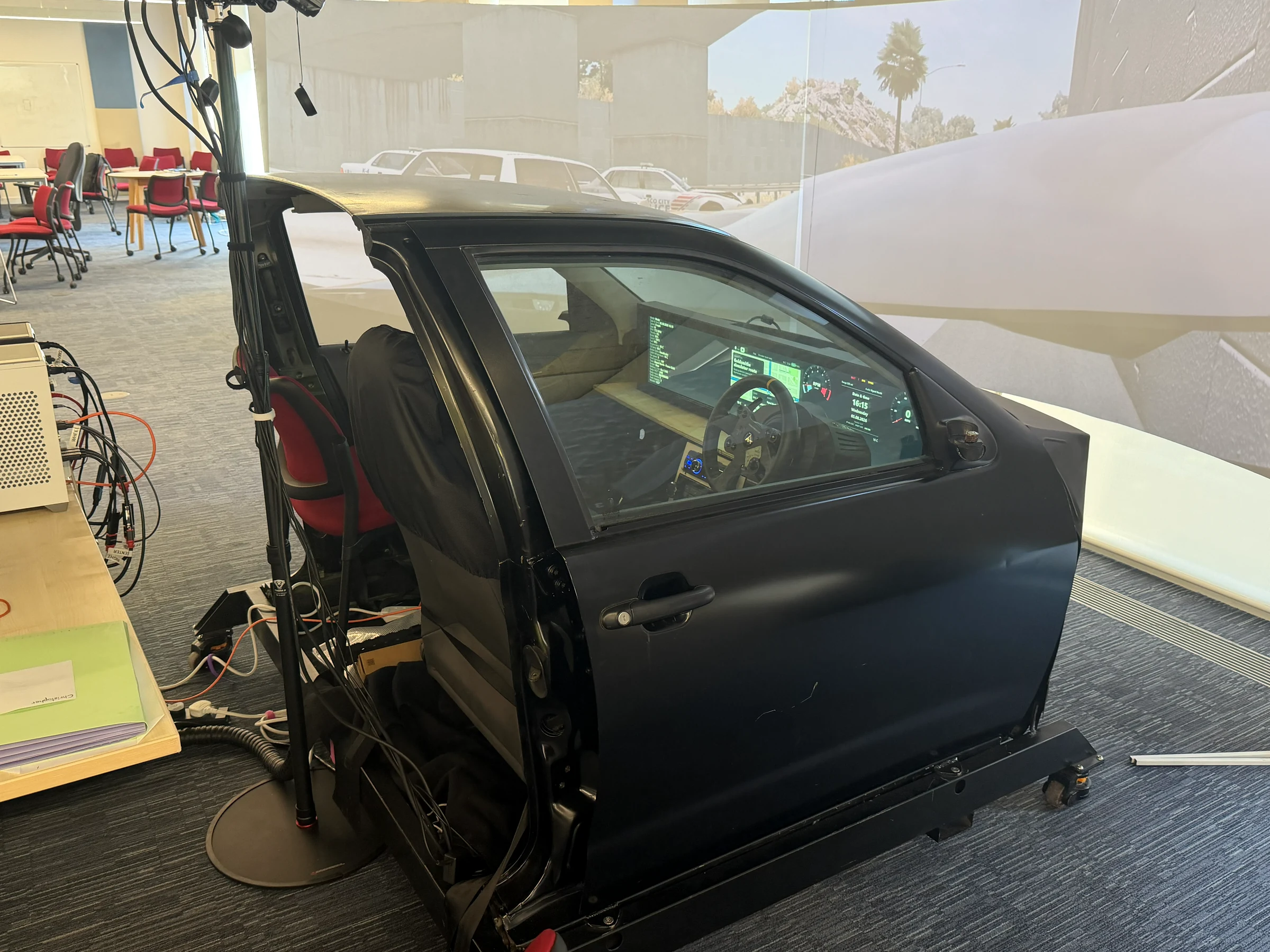 Side view of the Goldsmiths cockpit simulator, with the study display and controls inside and a projected driving scene around it.